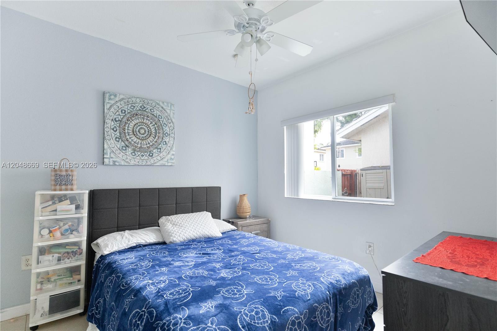 A bedroom features a bed with a blue turtle-patterned blanket, a ceiling fan, and window — 249 SE 32nd Ave, Homestead FL 33033, HOMESTEAD, FL