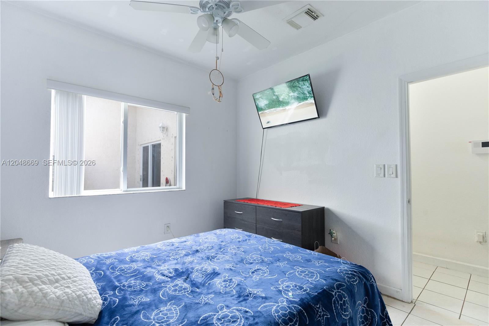 A bedroom features a bed with a blue turtle-patterned blanket, a ceiling fan, and television — 249 SE 32nd Ave, Homestead FL 33033, HOMESTEAD, FL
