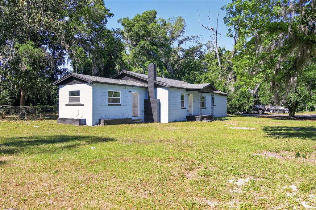 A single-story light blue house with a dark chimney sits on a grassy lot — 1308 SW 5TH STREET, OCALA, FL