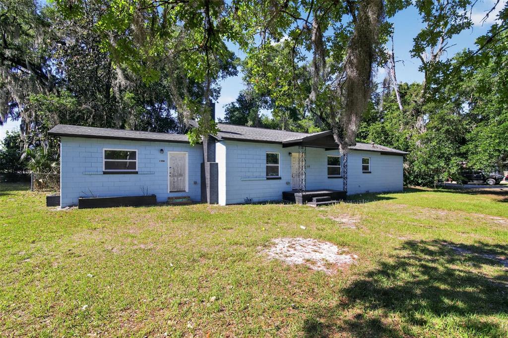 A light blue, single-story concrete block house sits on a grassy lot with mature trees — 1308 SW 5TH STREET, OCALA, FL