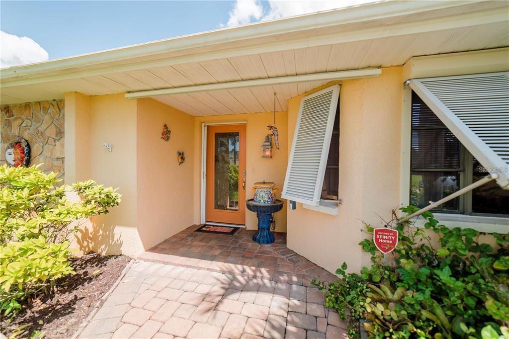 The front entrance features a brick walkway, an orange door, and a small fountain — 145 BUNKER ROAD, ROTONDA WEST, FL
