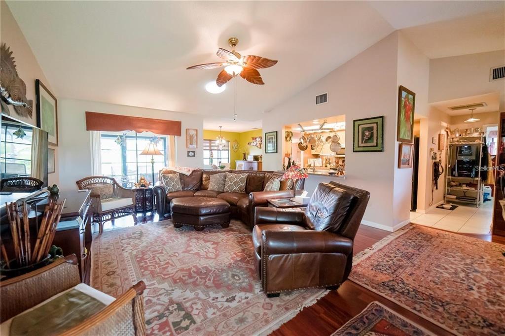 A living room features a leather sectional, a matching armchair, and patterned area rugs — 145 BUNKER ROAD, ROTONDA WEST, FL