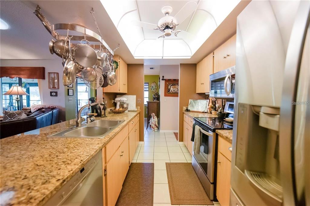 A kitchen with light wood cabinets, granite countertops, stainless steel appliances, and a hanging pot rack — 145 BUNKER ROAD, ROTONDA WEST, FL
