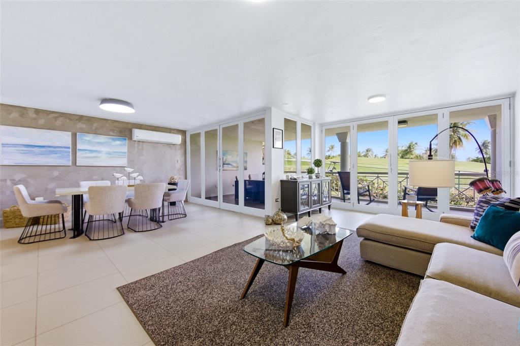 A bright living and dining area features tile floors, glass doors, and a golf course view — K4 COSTA DORADA UNIT 58, DORADO, PR