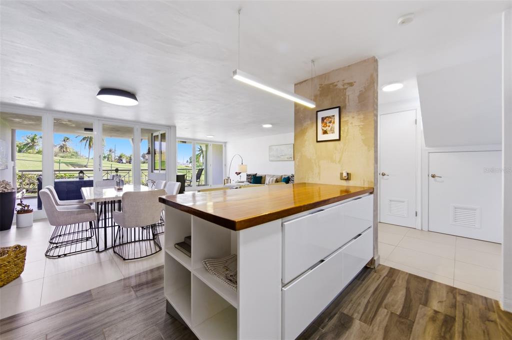 A modern kitchen island with a wood countertop sits in an open-concept living and dining area — K4 COSTA DORADA UNIT 58, DORADO, PR