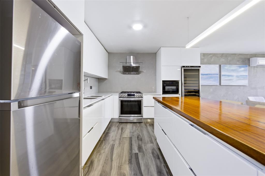 A modern kitchen features white cabinetry, stainless steel appliances, and a wooden island countertop — K4 COSTA DORADA UNIT 58, DORADO, PR