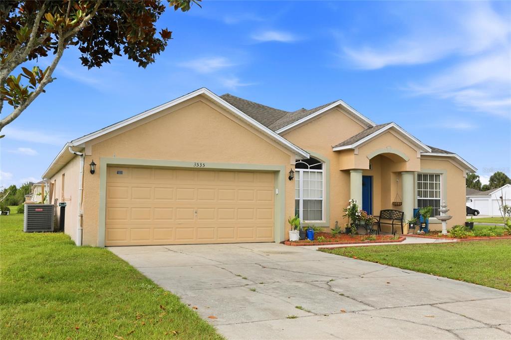 A single-story tan house with a two-car garage and a covered front entryway — 3535 BEAU CHENE DRIVE, KISSIMMEE, FL