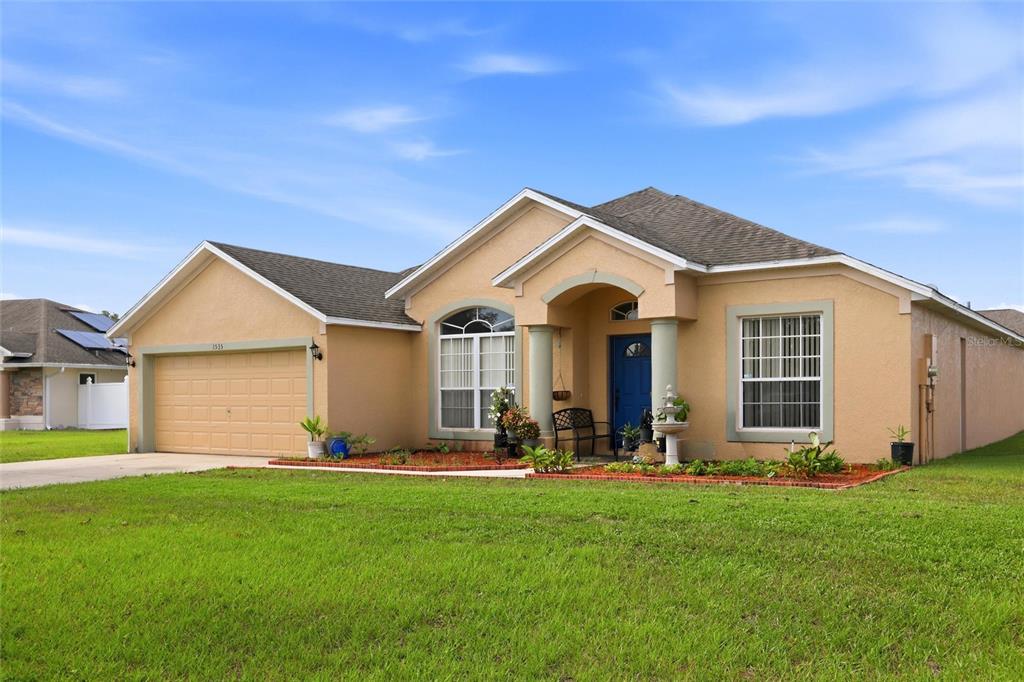 A single-story house with a tan stucco exterior, a blue front door, and a garage — 3535 BEAU CHENE DRIVE, KISSIMMEE, FL
