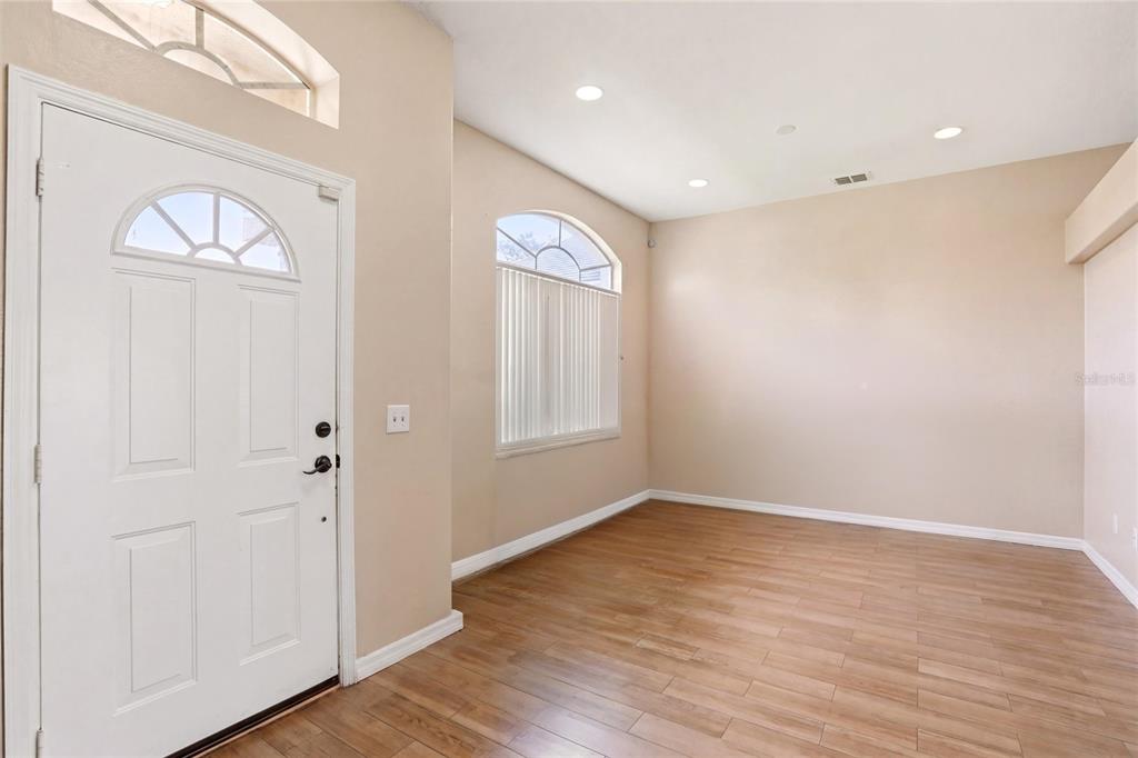An empty room with light wood-look flooring, beige walls, recessed lighting, and an arched window — 3535 BEAU CHENE DRIVE, KISSIMMEE, FL
