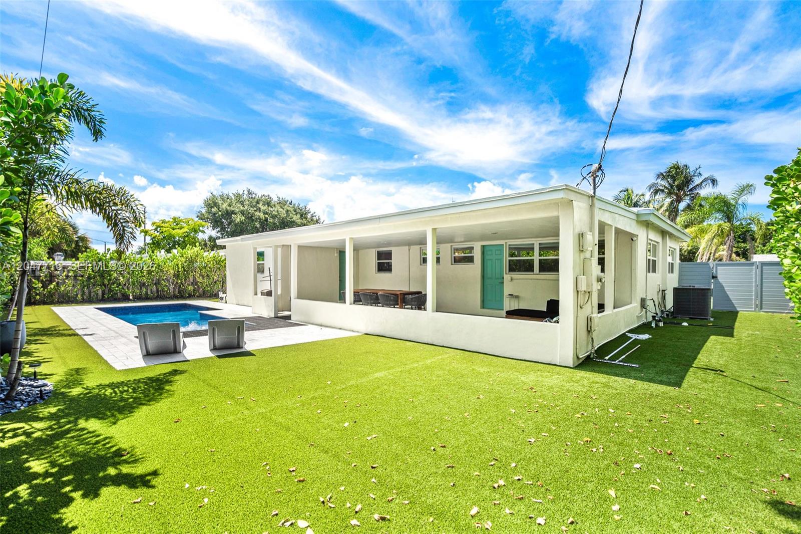A backyard features a swimming pool, artificial turf, and a covered patio with a turquoise door — 190 NE 21st St, Boca Raton FL 33431, BOCA RATON, FL