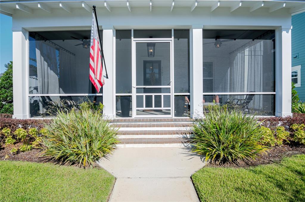 A front view of a house with a screened-in porch, brick steps, and an American flag — 1101 EAGLES PASS WAY, WINTER GARDEN, FL