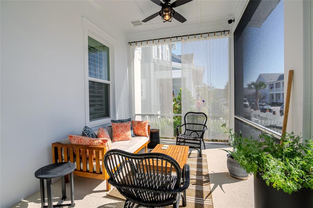 A screened-in porch features a wooden sofa, two black chairs, a coffee table, and plants — 1101 EAGLES PASS WAY, WINTER GARDEN, FL