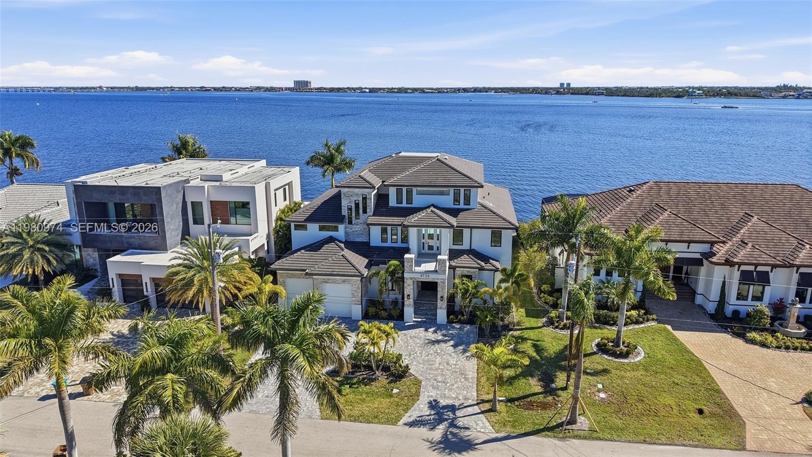 An aerial view shows three waterfront houses with palm trees and a paved driveway — 5735 Riverside Dr, Cape Coral FL 33904, CAPE CORAL, FL