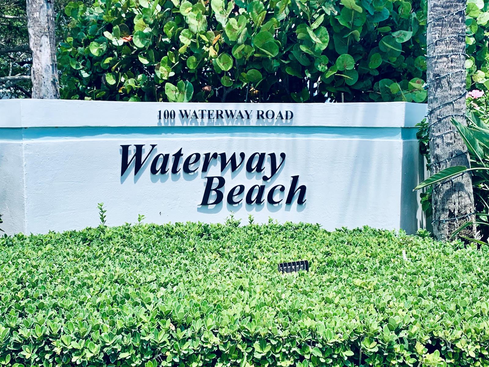 A sign for Waterway Beach sits in front of a hedge and a white wall — 100 Waterway Road # A304, Tequesta FL 33469, TEQUESTA, FL