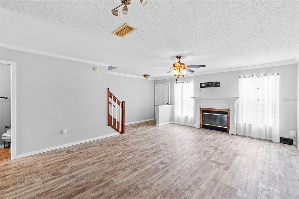 A living room with light gray walls, wood-look flooring, a fireplace, and a ceiling fan — 5314 ABINGER COURT, TAMPA, FL