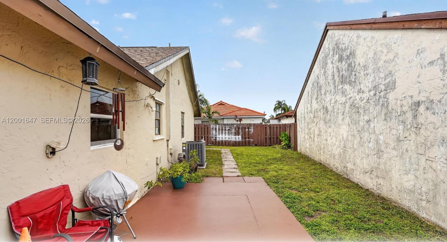 A side yard features a small concrete patio, a grill, and a grassy area between houses — 7010 SW 103rd Pl, Miami FL 33173, MIAMI, FL