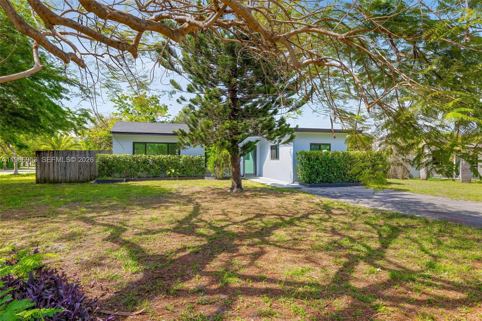 A single-story house with a flat roof, light-colored exterior, and a large front yard tree — 1998 NE 180th St, North Miami Beach FL 33162, NORTH MIAMI BEACH, FL