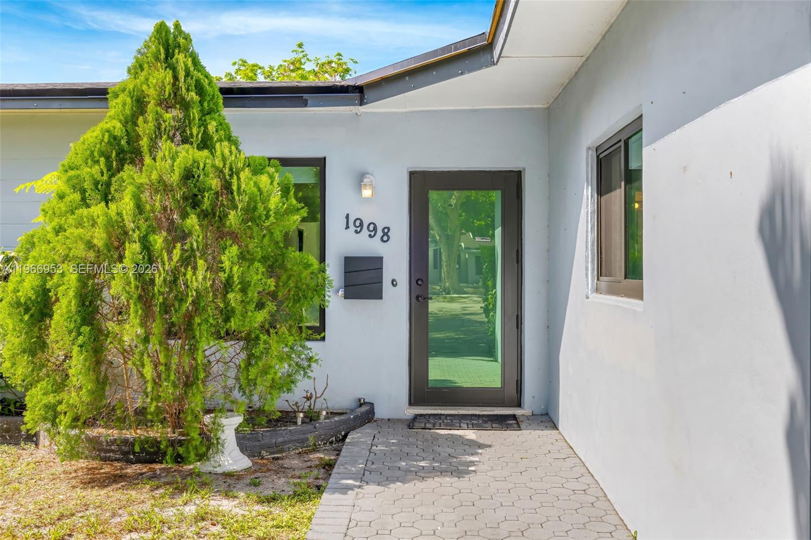A paved walkway leads to a front door with a glass panel and house numbers — 1998 NE 180th St, North Miami Beach FL 33162, NORTH MIAMI BEACH, FL