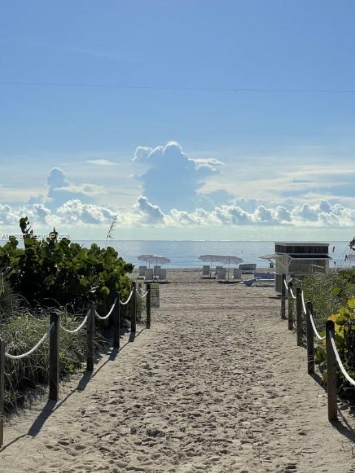 A sandy path leads through grassy dunes toward the ocean under a bright sun — 335 Ocean Dr # 214, Miami Beach FL 33139, MIAMI BEACH, FL