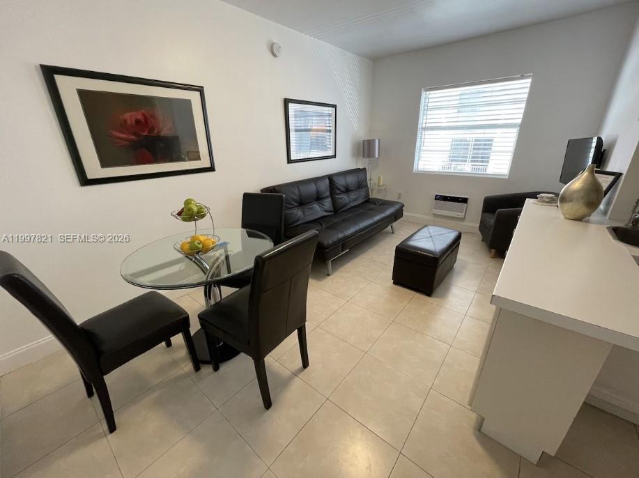 A living and dining area features a glass table, black sofa, and tile flooring — 335 Ocean Dr # 214, Miami Beach FL 33139, MIAMI BEACH, FL