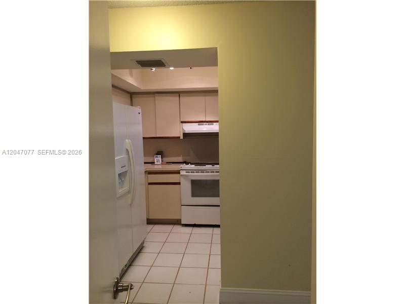 A kitchen with white appliances, light-colored cabinets, and white tile flooring — 8977 SW 123rd Ct # 202, Miami FL 33186, MIAMI, FL