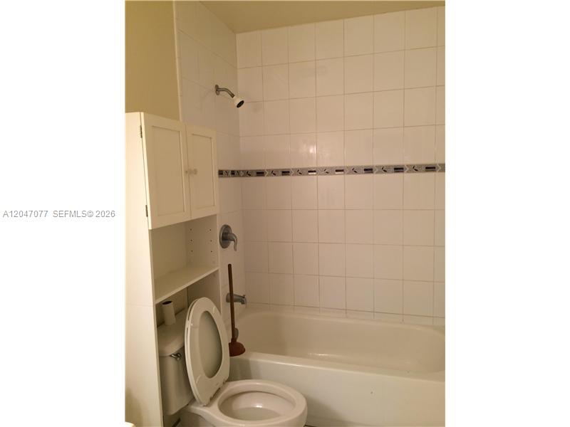 A bathroom features a white bathtub, a toilet, and a white storage cabinet — 8977 SW 123rd Ct # 202, Miami FL 33186, MIAMI, FL