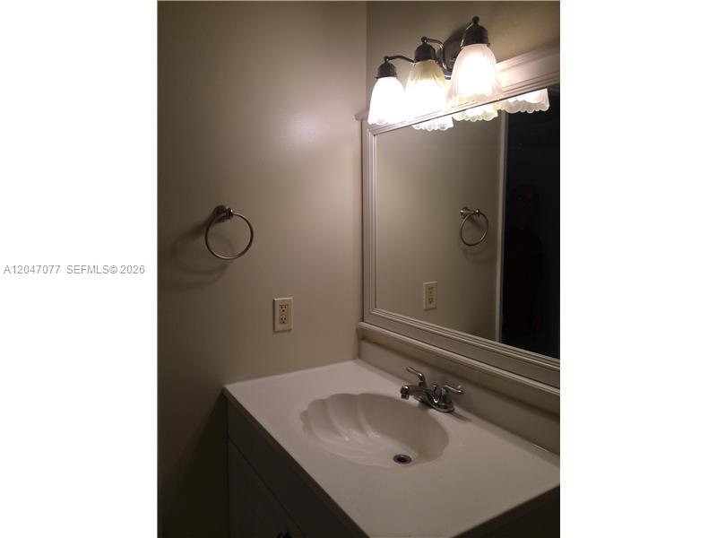 A bathroom vanity features a white shell-shaped sink, a mirror, and a three-light fixture — 8977 SW 123rd Ct # 202, Miami FL 33186, MIAMI, FL