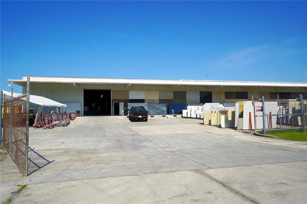 A large industrial warehouse exterior features a concrete lot with numerous stone slab displays — 4500 CARMICHAEL AVENUE UNIT Building 4, SARASOTA, FL