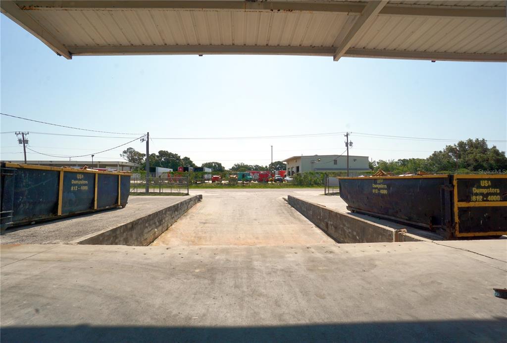 A concrete loading dock area features two large blue dumpsters under a metal canopy — 4500 CARMICHAEL AVENUE UNIT Building 4, SARASOTA, FL