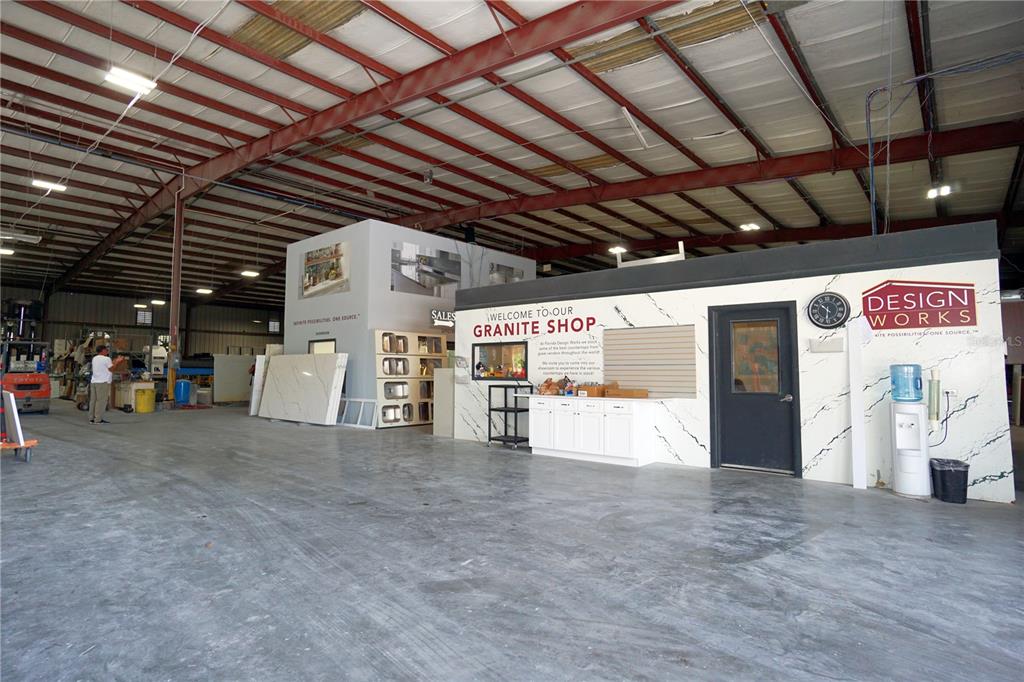 A spacious industrial warehouse interior features a granite showroom office with white cabinets and signage — 4500 CARMICHAEL AVENUE UNIT Building 4, SARASOTA, FL