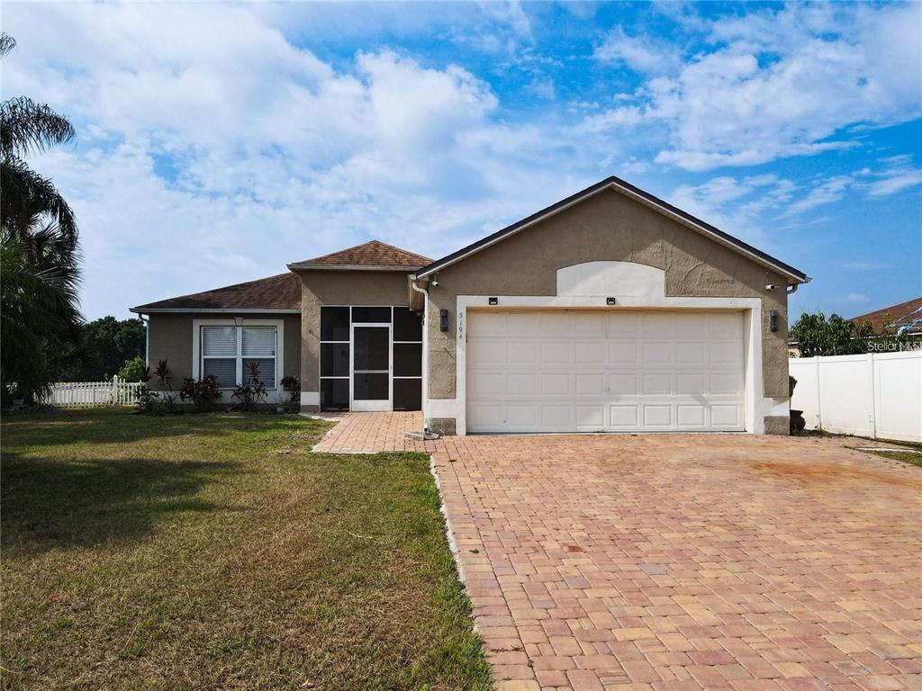 A single-story house with a tan stucco exterior, a two-car garage, and a screened entryway — 3194 WINDMILL POINT BOULEVARD, KISSIMMEE, FL