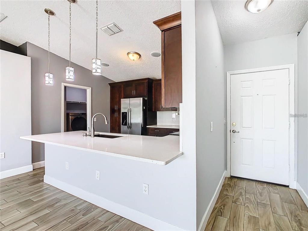 A kitchen with a white island countertop, dark wood cabinets, and a white front door — 3194 WINDMILL POINT BOULEVARD, KISSIMMEE, FL