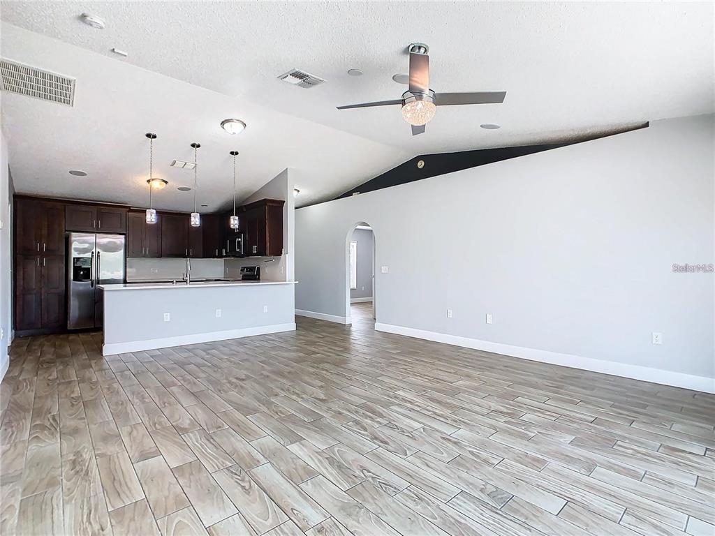 A kitchen with dark cabinets and a breakfast bar opens to a large living area — 3194 WINDMILL POINT BOULEVARD, KISSIMMEE, FL