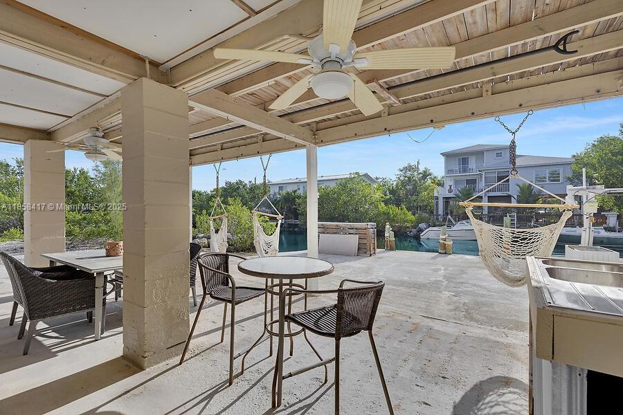 A covered outdoor patio features a dining set, hammock, and waterfront views — 813 Hawksbill Ln, Sugarloaf FL 33042, SUGARLOAF, FL