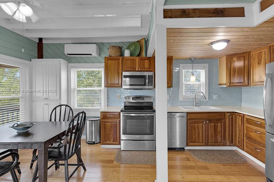 A kitchen features wood cabinets, stainless steel appliances, light blue tile backsplash, and a dining area — 813 Hawksbill Ln, Sugarloaf FL 33042, SUGARLOAF, FL