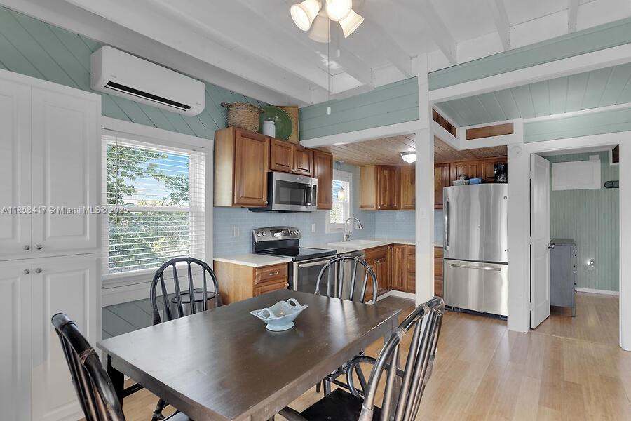 A kitchen and dining area features wood cabinets, stainless steel appliances, and light blue walls — 813 Hawksbill Ln, Sugarloaf FL 33042, SUGARLOAF, FL