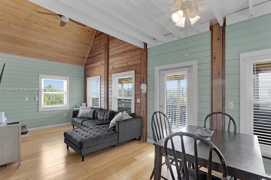 A living and dining area features wood-paneled walls, a vaulted ceiling, and light wood flooring — 813 Hawksbill Ln, Sugarloaf FL 33042, SUGARLOAF, FL