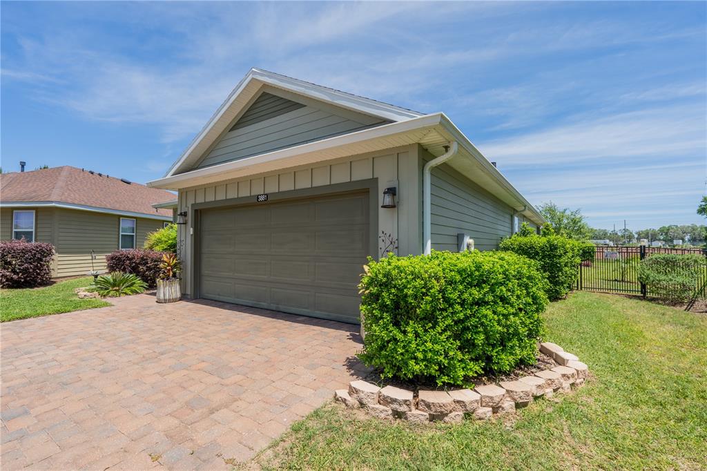 A view of a house exterior featuring a two-car garage, brick driveway, and landscaping — 3881 NW 46TH TERRACE, OCALA, FL