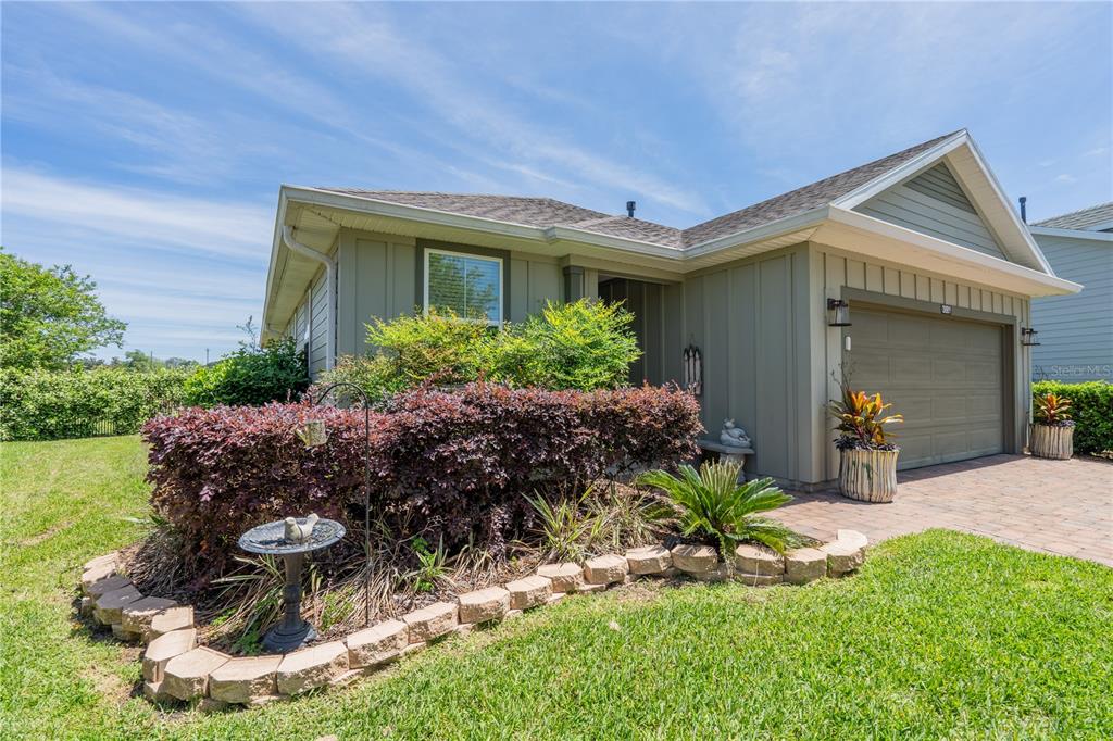 A single-story house with olive green siding, a two-car garage, and a landscaped front yard — 3881 NW 46TH TERRACE, OCALA, FL
