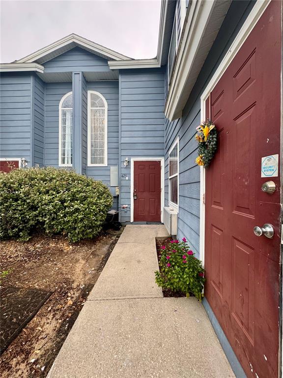 A concrete walkway leads to the red front doors of a blue-sided residential building — 425 CARIBBEAN DRIVE, DAVENPORT, FL
