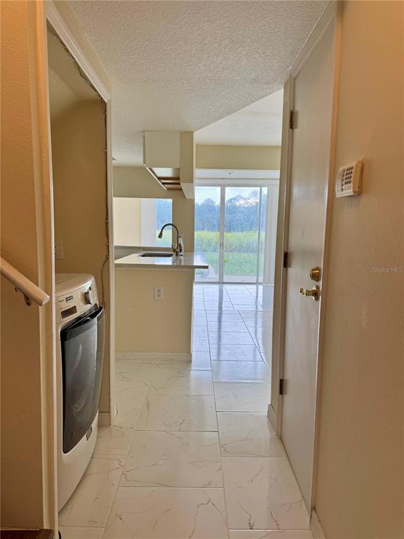 A hallway with a washer leads to a kitchen and a view of the outdoors — 425 CARIBBEAN DRIVE, DAVENPORT, FL