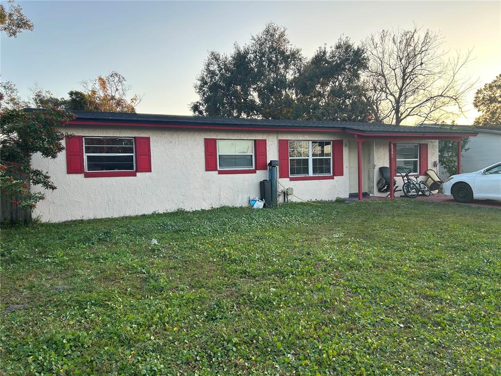 A single-story house with white stucco walls, red shutters, and a covered front porch — 5391 BOTANY COURT, ORLANDO, FL