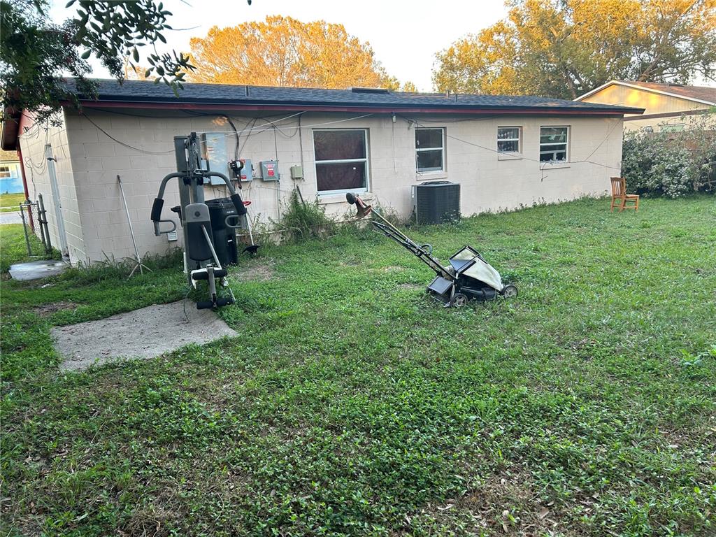The exterior of a beige concrete block house with a lawn, exercise equipment, and mower — 5391 BOTANY COURT, ORLANDO, FL