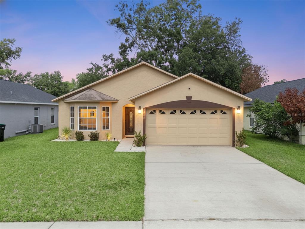 A single-story tan house with a two-car garage and a front-facing bay window — 2744 PALM ISLE WAY, ORLANDO, FL