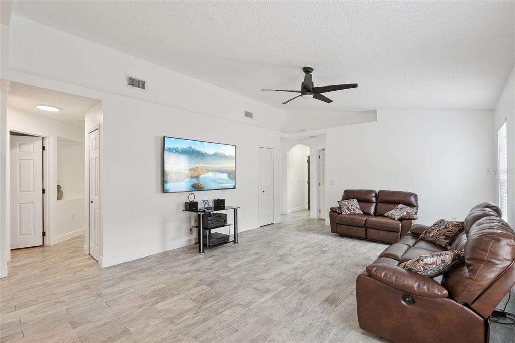 A living room features white walls, light wood-look tile flooring, a ceiling fan, and leather furniture — 2744 PALM ISLE WAY, ORLANDO, FL