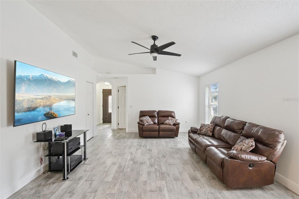 A living room features white walls, wood-look tile flooring, brown leather furniture, and a ceiling fan — 2744 PALM ISLE WAY, ORLANDO, FL