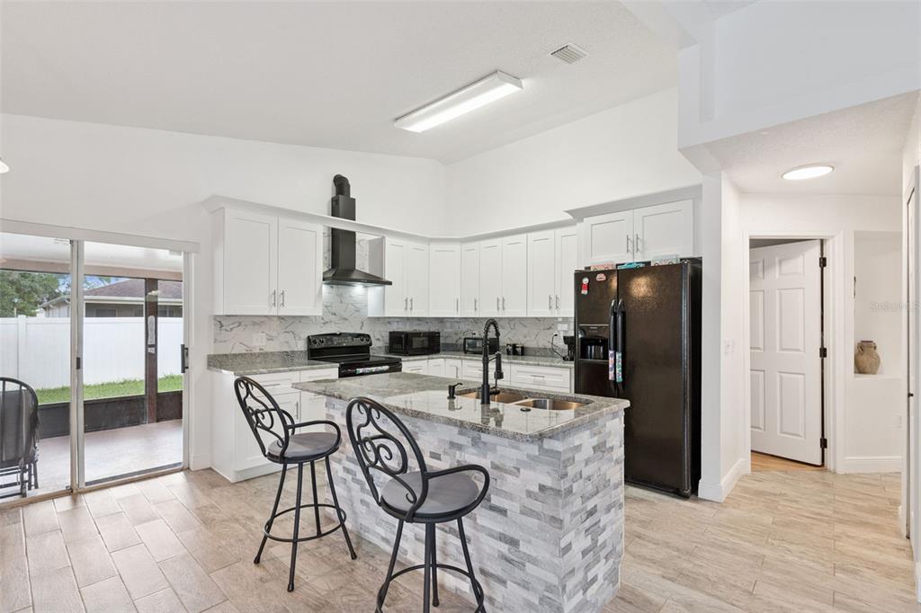 A kitchen with white cabinets, granite countertops, a stone-faced island, and black appliances — 2744 PALM ISLE WAY, ORLANDO, FL
