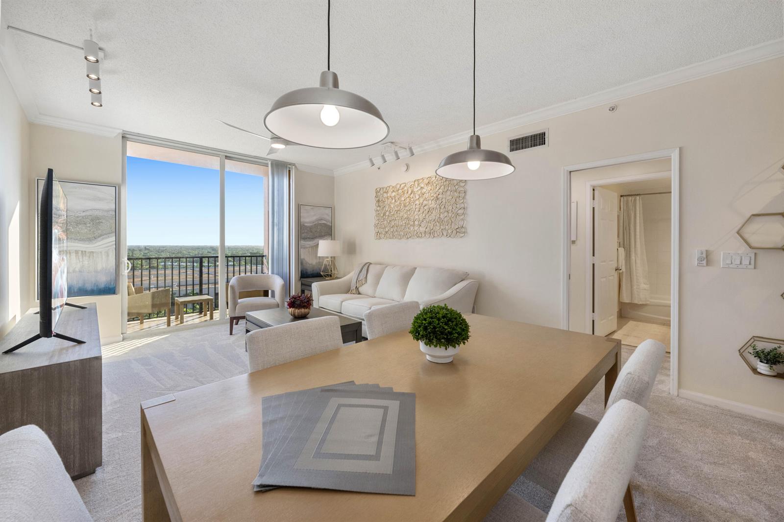 A dining area and living room feature neutral furniture, pendant lighting, and a balcony view — 651 Okeechobee Boulevard # 1107, West Palm Beach FL 33401, WEST PALM BEACH, FL