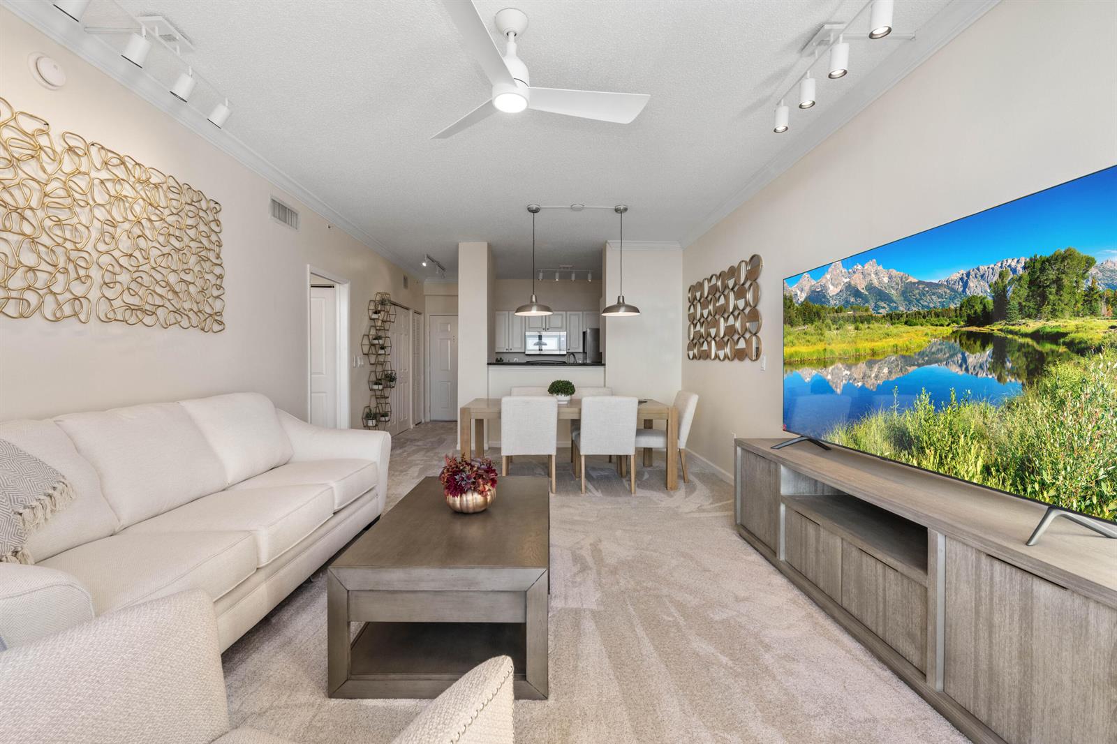 A living room with a white sofa, coffee table, and television facing a dining area — 651 Okeechobee Boulevard # 1107, West Palm Beach FL 33401, WEST PALM BEACH, FL