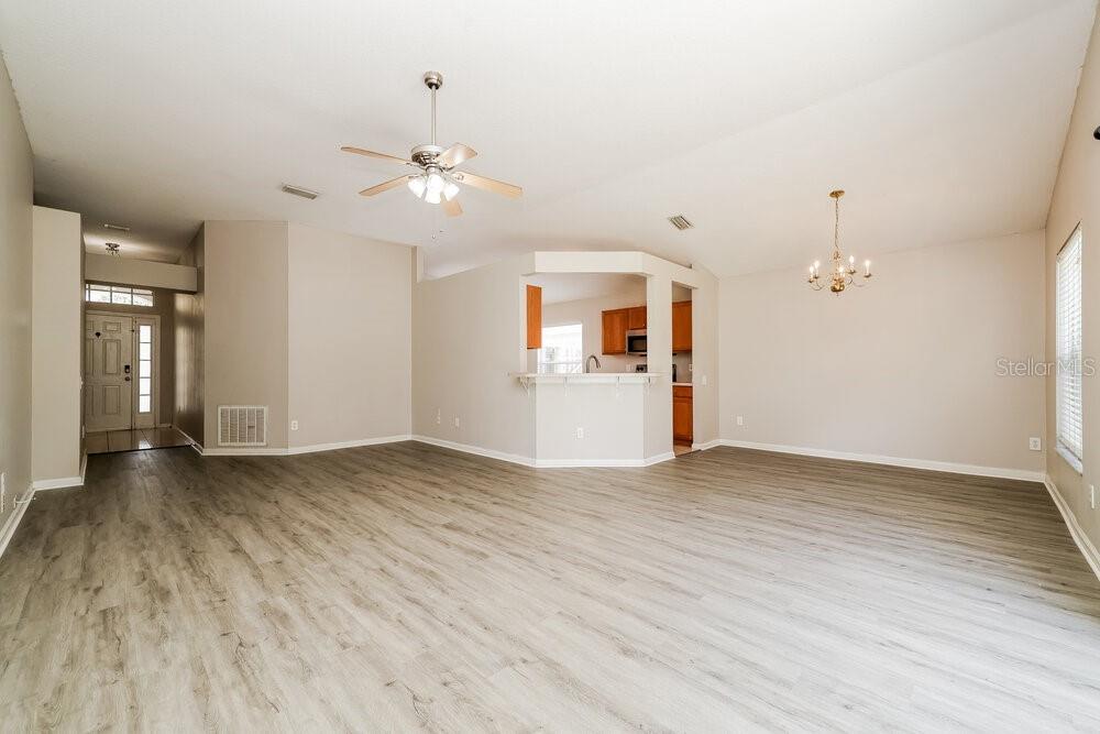A spacious living room features light wood-look flooring, a ceiling fan, and a kitchen pass-through — 10422 HUNTERS HAVEN BOULEVARD, RIVERVIEW, FL